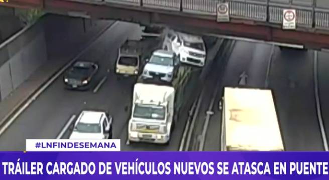 Tráiler cargado de vehículos nuevos se atasca en puente